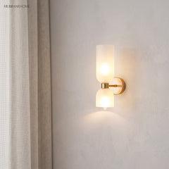 Glass wall sconce lit beside linen curtains in a quiet corner