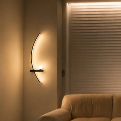 Black arc wall sconce viewed from an angle with a soft upward glow
