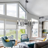 Black iron candle chandelier in a bright living room with tall windows