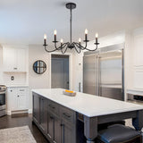 Six light black candle chandelier above a grey kitchen island in a white kitchen