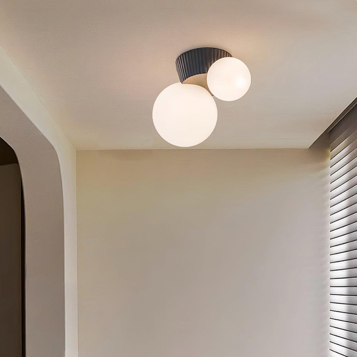 Black canopy globe ceiling light lit in the corner of a plain white hallway