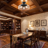 Black clear-glass drum ceiling light on a wood coffered ceiling over a dining table
