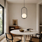 Black oval frame glass globe pendant over a round marble dining table and rattan chairs