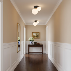 Black canopy globe lights above a panelled hallway with a framed landscape