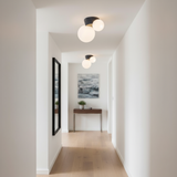 Black canopy globe lights lining a plain white corridor with an oak floor
