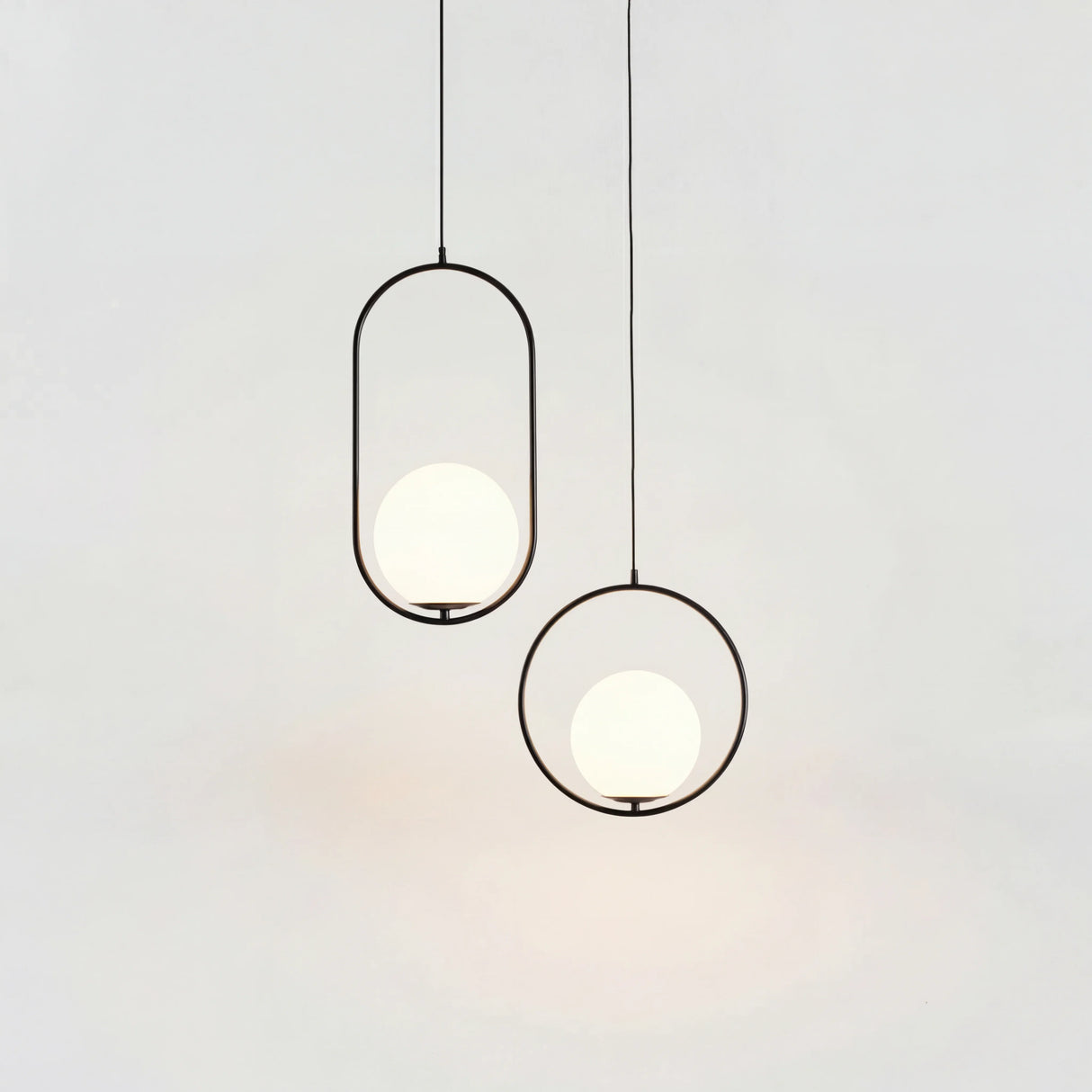 Black and gold oval frame pendant lights with opal glass globes hanging together