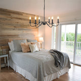 Black candle chandelier above a bed with a reclaimed timber feature wall