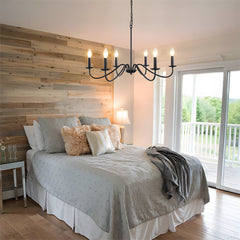 Black candle chandelier above a bed with a reclaimed timber feature wall