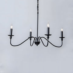 Four light black candle chandelier with curved arms against a pale grey wall