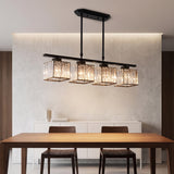 Four light black linear pendant light glowing above a walnut dining table