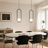 Pair of black oval frame glass globe pendants above a long dining table near a window