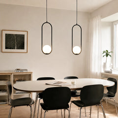 Pair of black oval frame glass globe pendants above a long dining table near a window