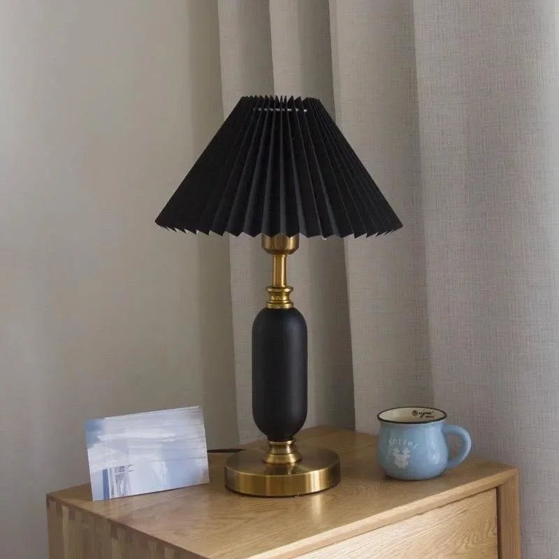 Black pleated table lamp with brass column base, studio view