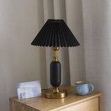 Black pleated table lamp with brass column base, studio view