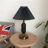 Black pleated table lamp beside a sofa pillow