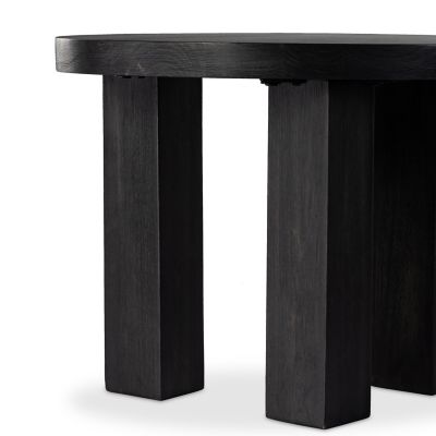Black round wood side table styled beside modern lounge chair