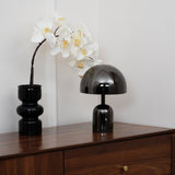 Black gloss lamp standing beside a black vase holding a white orchid
