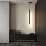 Two black tube pendant lights lighting a dark minimalist entryway bench