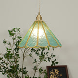 Blue glass pendant seen through green branches with the panels lit