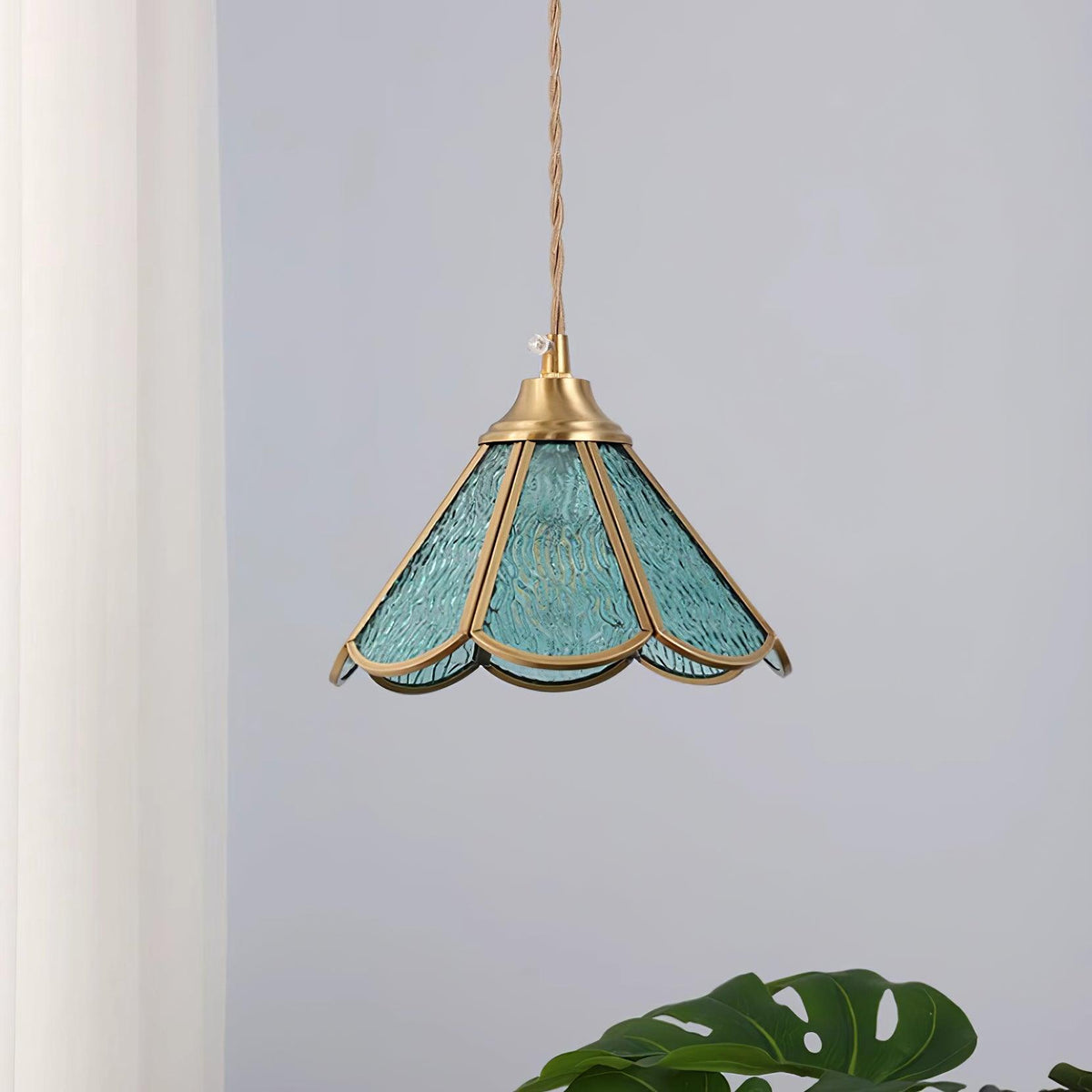 Blue glass pendant hanging beside a pale curtain with the frame clearly visible