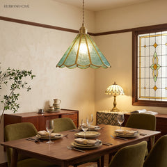Blue glass pendant above a set dining table in a room with leaded windows