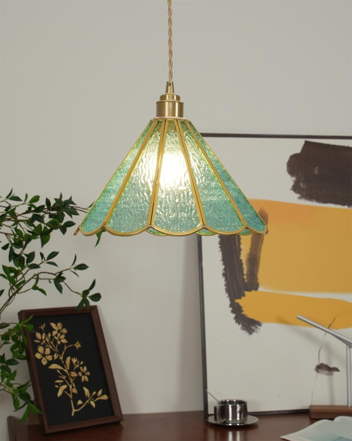 Side view of the blue glass pendant unlit beside trailing indoor foliage