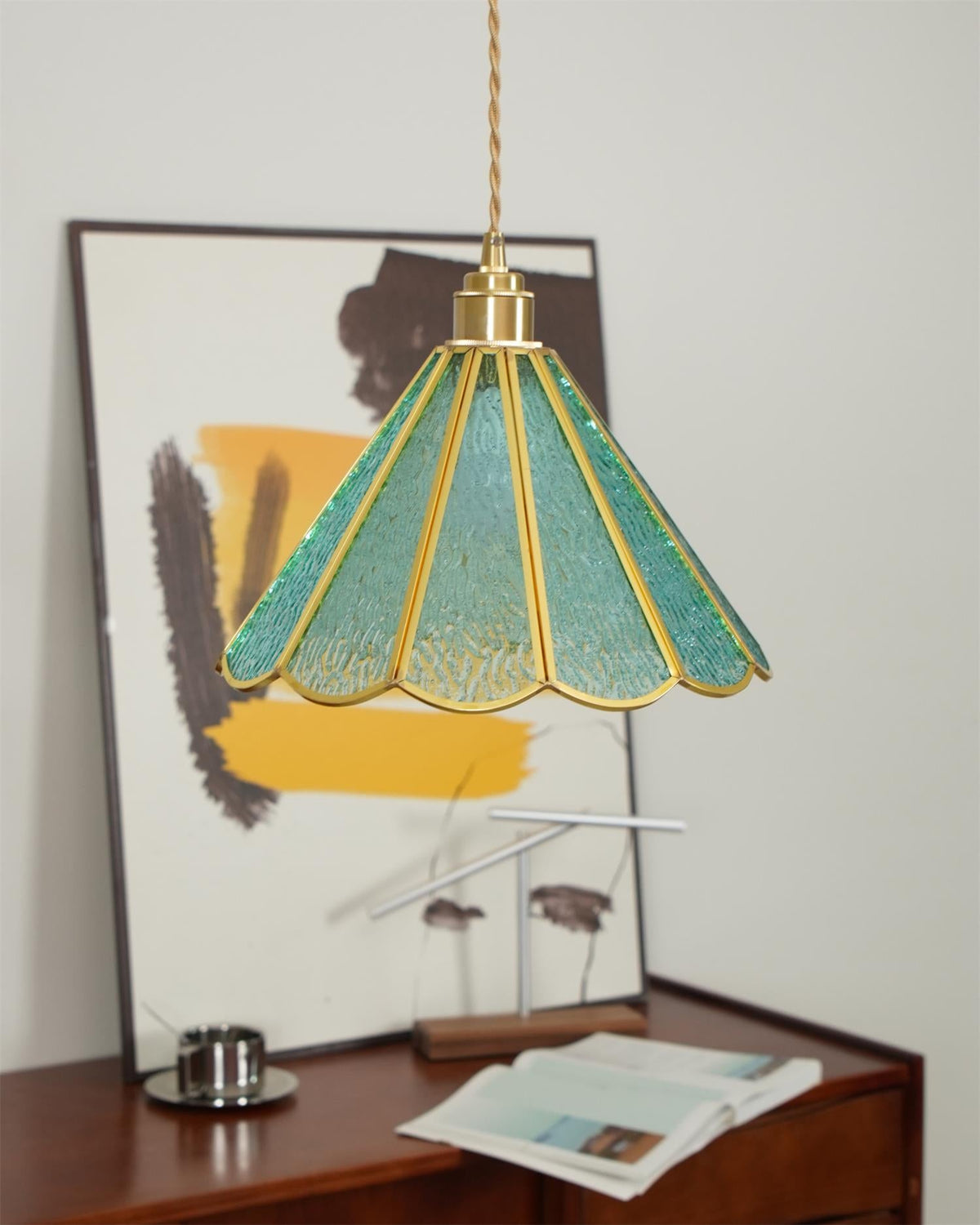 Blue glass pendant above a walnut sideboard with a framed abstract print