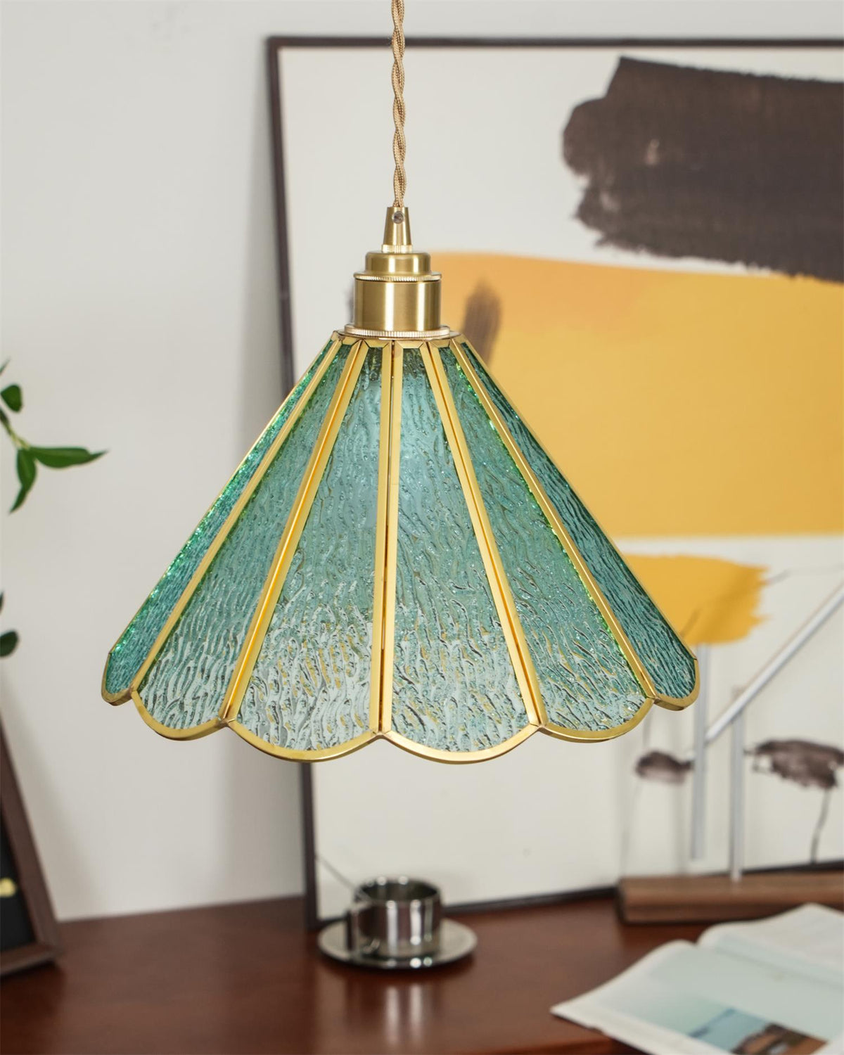 Blue glass pendant hung low over a timber sideboard and a yellow artwork