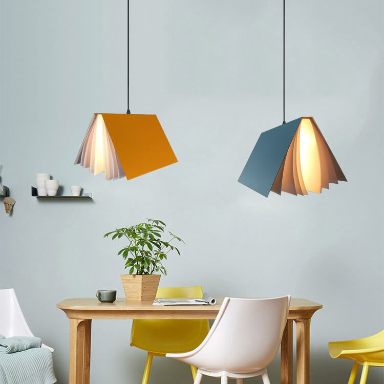 Orange and blue book pendant lights hanging over a dining table