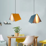 Orange and blue book pendant lights hanging over a dining table