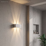 White up and down LED wall sconce beside a concrete wall niche