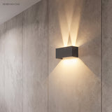 Grey modern wall sconce casting soft twin beams in a hallway