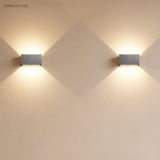 Pair of aluminum up down sconces mounted along a bright wall