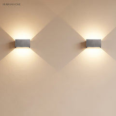 Pair of aluminum up down sconces mounted along a bright wall