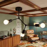 Black branch ceiling light with bare bulbs above a retro living room