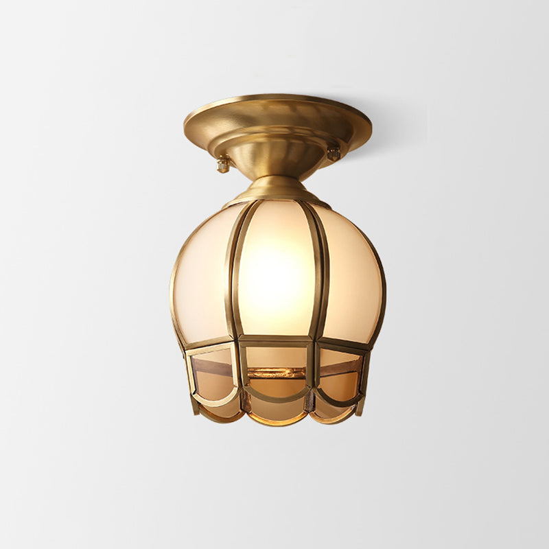 Tall caged glass panel shade in a brass frame on plain white