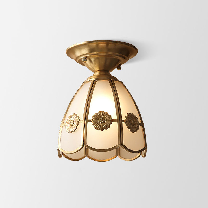 Rosette trimmed glass panel shade in a brass frame on plain white