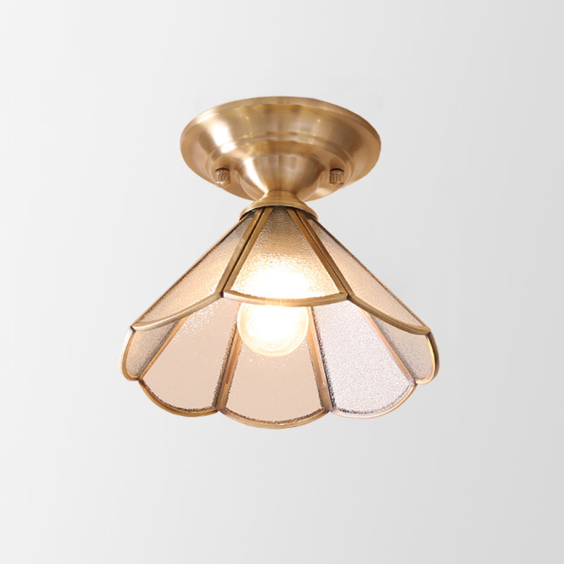 Wide scalloped glass panel shade in a brass frame on plain white