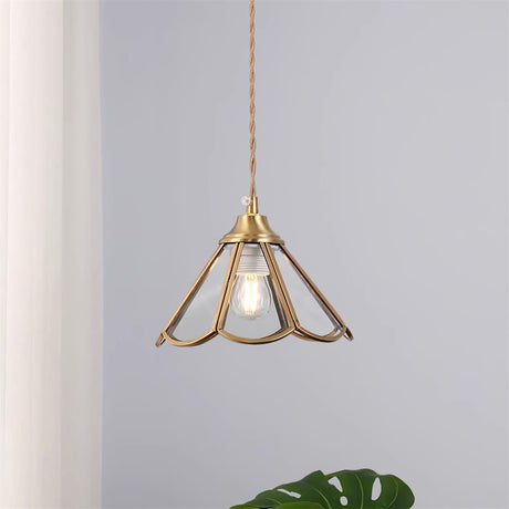 Brass framed pendant with a bare filament bulb hanging against a plain wall