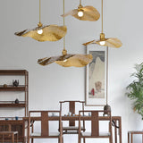 Cluster of brass lotus leaf pendant lights over a wooden dining table