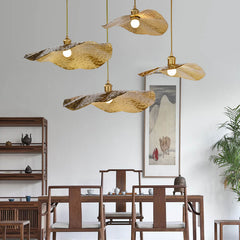 Cluster of brass lotus leaf pendant lights over a wooden dining table