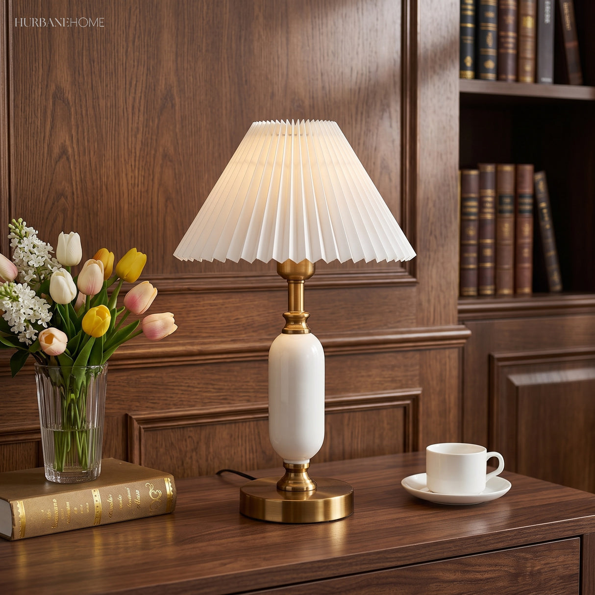 White brass table lamp with pleated shade on a study desk beside flowers