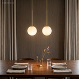 Two brass stem globe pendants above a walnut dining table setting