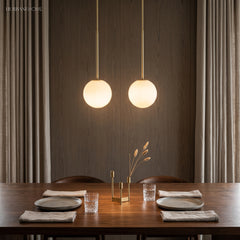 Two brass stem globe pendants above a walnut dining table setting