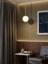 Brass and black stem globe pendants beside a leather armchair corner