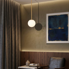 Brass and black stem globe pendants beside a leather armchair corner