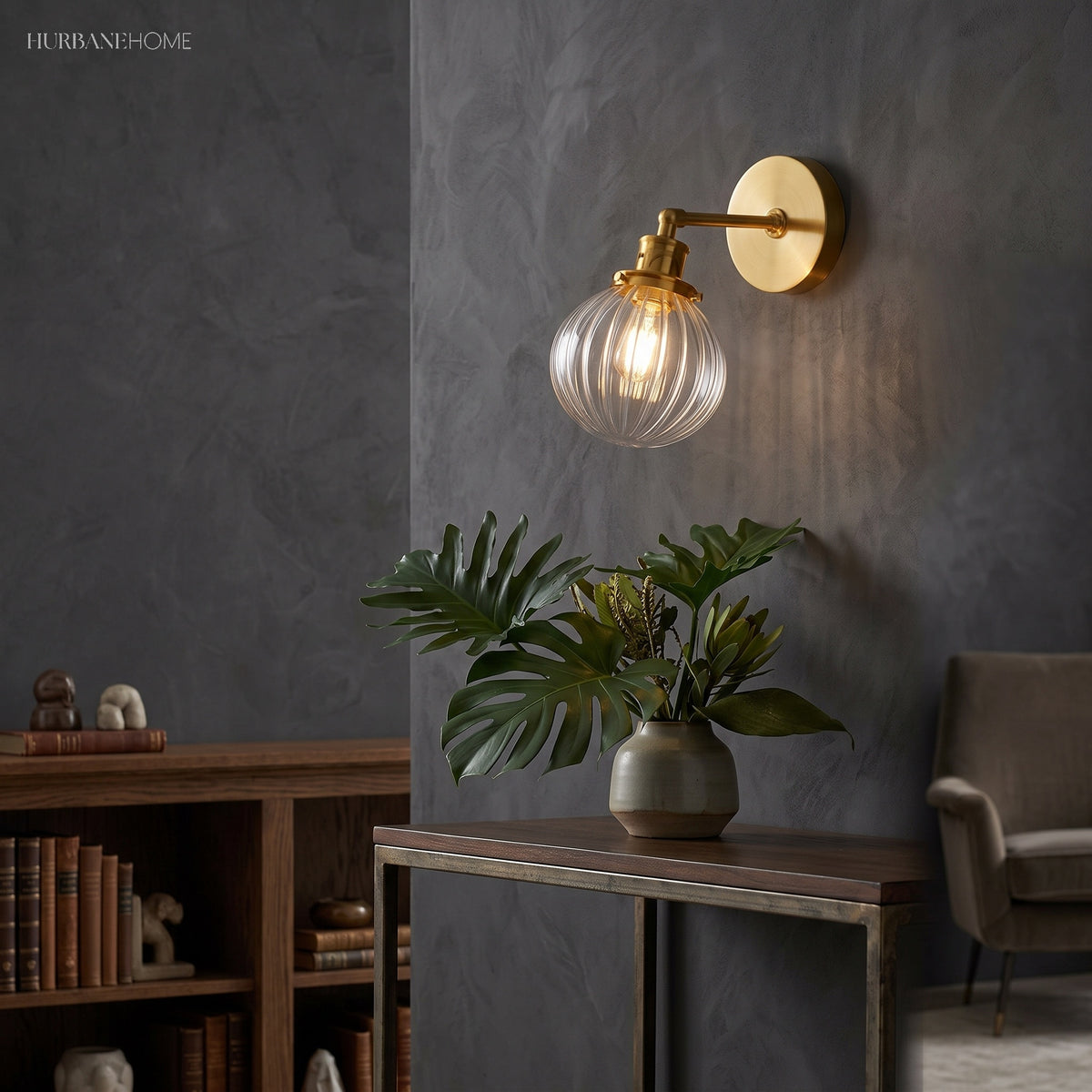 Lit brass sconce with clear ribbed glass beside a dark study bookcase
