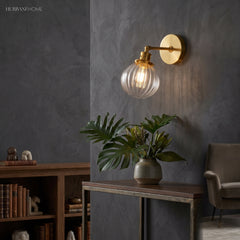 Lit brass sconce with clear ribbed glass beside a dark study bookcase