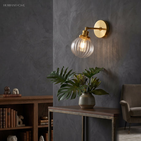 Lit brass sconce with clear ribbed glass beside a dark study bookcase