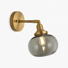 Brass wall sconce with a smoky grey translucent glass shade and filament bulb
